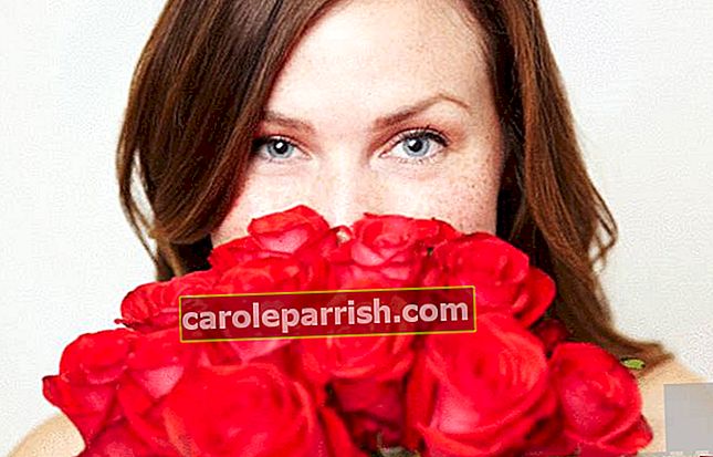 una donna respira un bouquet di rose rosse