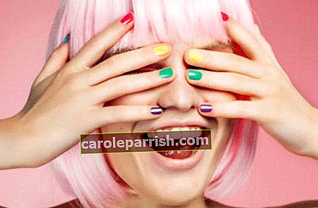 Eine Frau versteckt ihre Augen unter den Händen mit bunten Fingernägeln