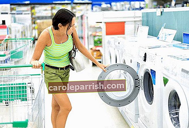 brunett-kvinna-öppnar-tvättmaskin-fönster-i-en-avdelning-av-fem-tvättmaskiner-i-butik