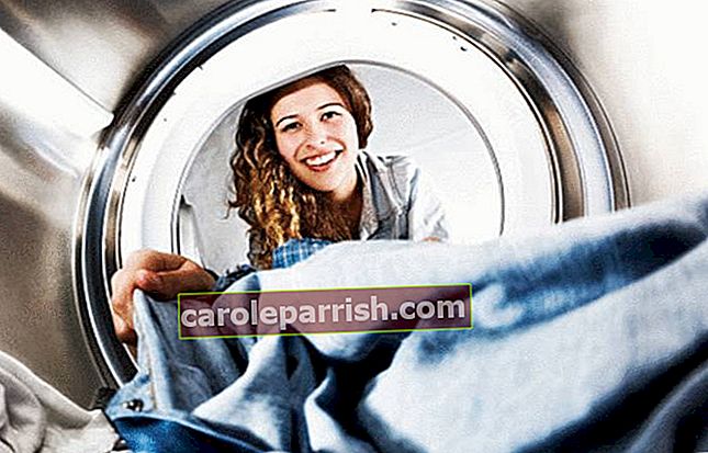 seorang wanita memasukkan ke dalam mesin cucian yang noda-nodanya telah diatasi dengan penghilang noda
