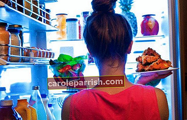 Um Gewicht zu verlieren, zögert eine Frau vor ihrem Kühlschrank zwischen Gemüse und Fleisch