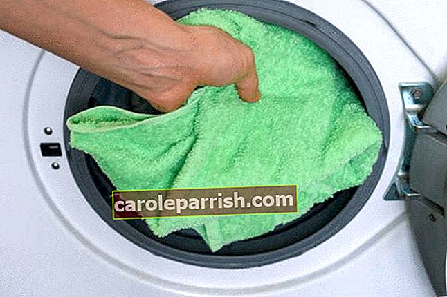 Einlegen eines grünen Handtuchs von Hand in einen Trockner mit Frontöffnung