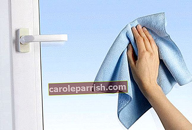 la mano di una donna con un panno blen pulisce una macchia sul vetro